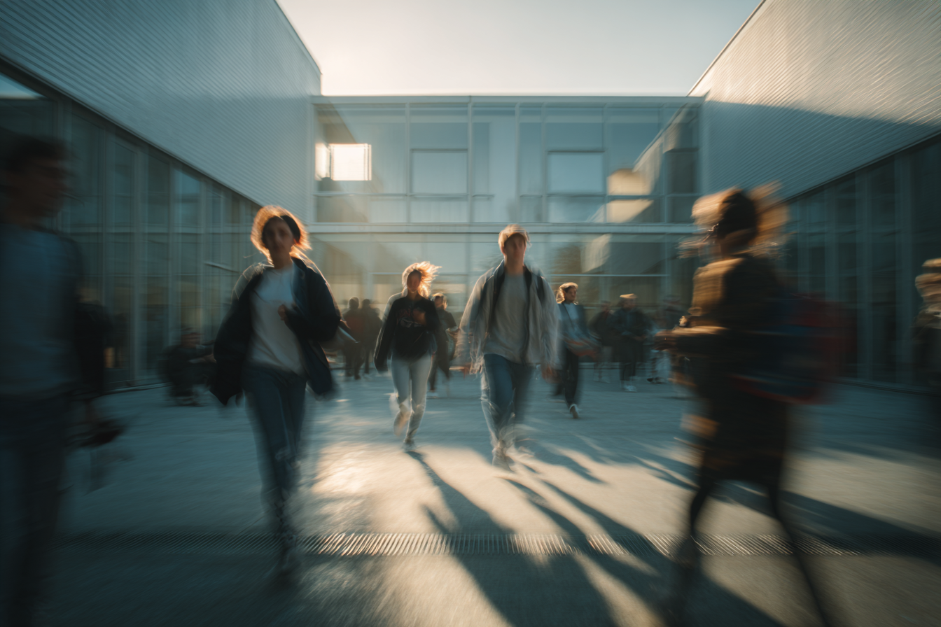 Students walking through the Bauhaus Dessau courtyard in warm daylight, motion blur and long shadows across modernist architecture, blending human movement with geometric clarity.